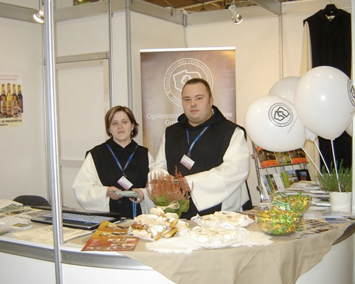 Na stoisku Tour Salon 2011 … Więcej Osobami pracującymi w tym roku na stoisku Ogólnopolskiego Stowarzyszenia Gmin Cysterskich byli ubrani w habity cysterskie pracownicy Urzędu Miejskiego w Kuźni Raciborskiej – Monika Jordan oraz Marcin Gałuszka-Biernacki
